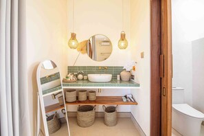 A bathroom with a white sink, green tiled backsplash, and a wooden shelf with baskets. - Chic Villa Living, Hidden in the Calm of Tumbak Bayuh (Canggu)