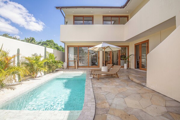 A modern two-story house with a swimming pool, outdoor seating, and a view of the surrounding greenery. - Chic Villa Living, Hidden in the Calm of Tumbak Bayuh (Canggu)