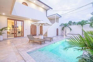 A modern house with a swimming pool, two lounge chairs, and a staircase leading to the upper floor. - Chic Villa Living, Hidden in the Calm of Tumbak Bayuh (Canggu)
