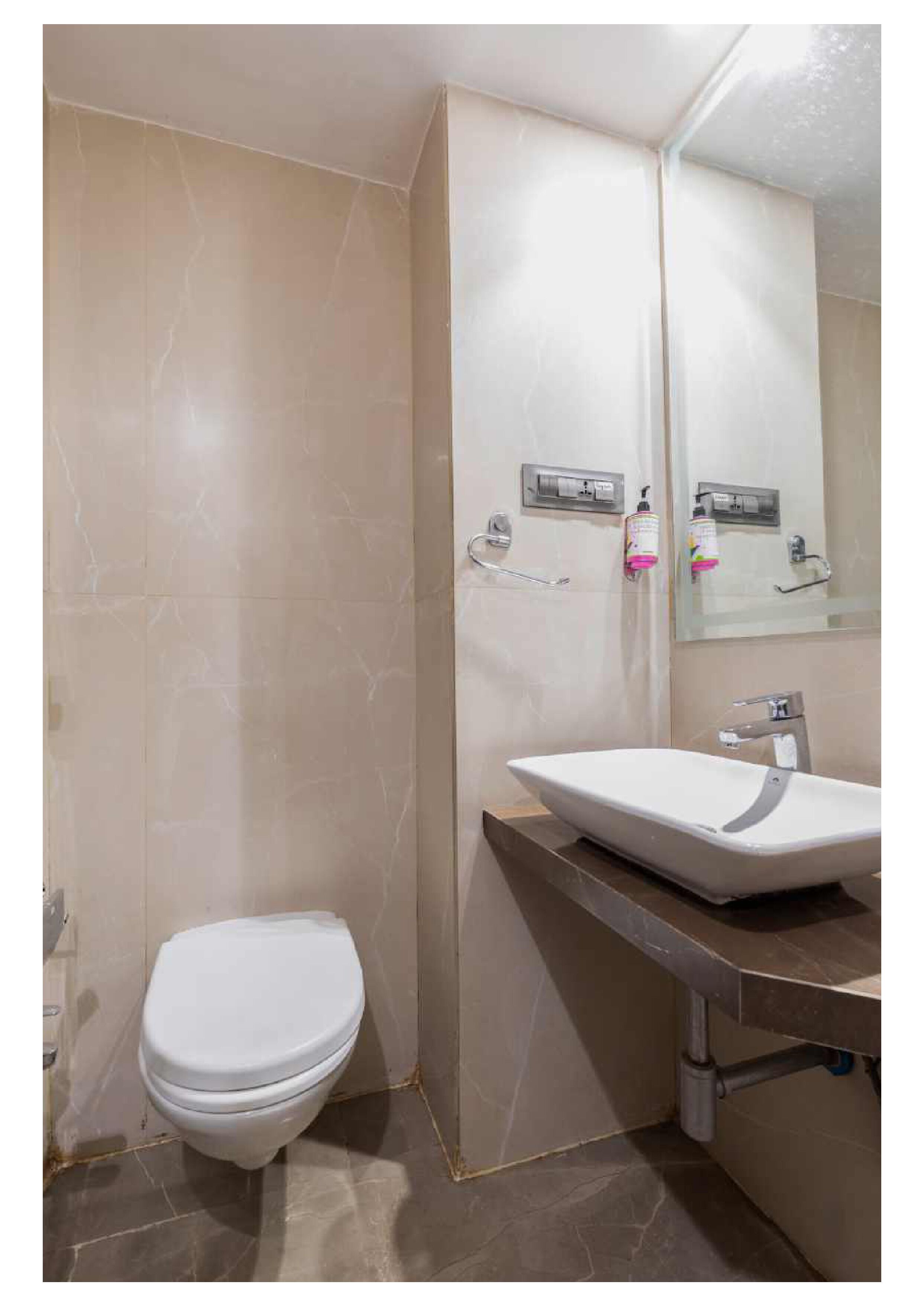 Et badeværelse med toilet, håndvask og spejl.