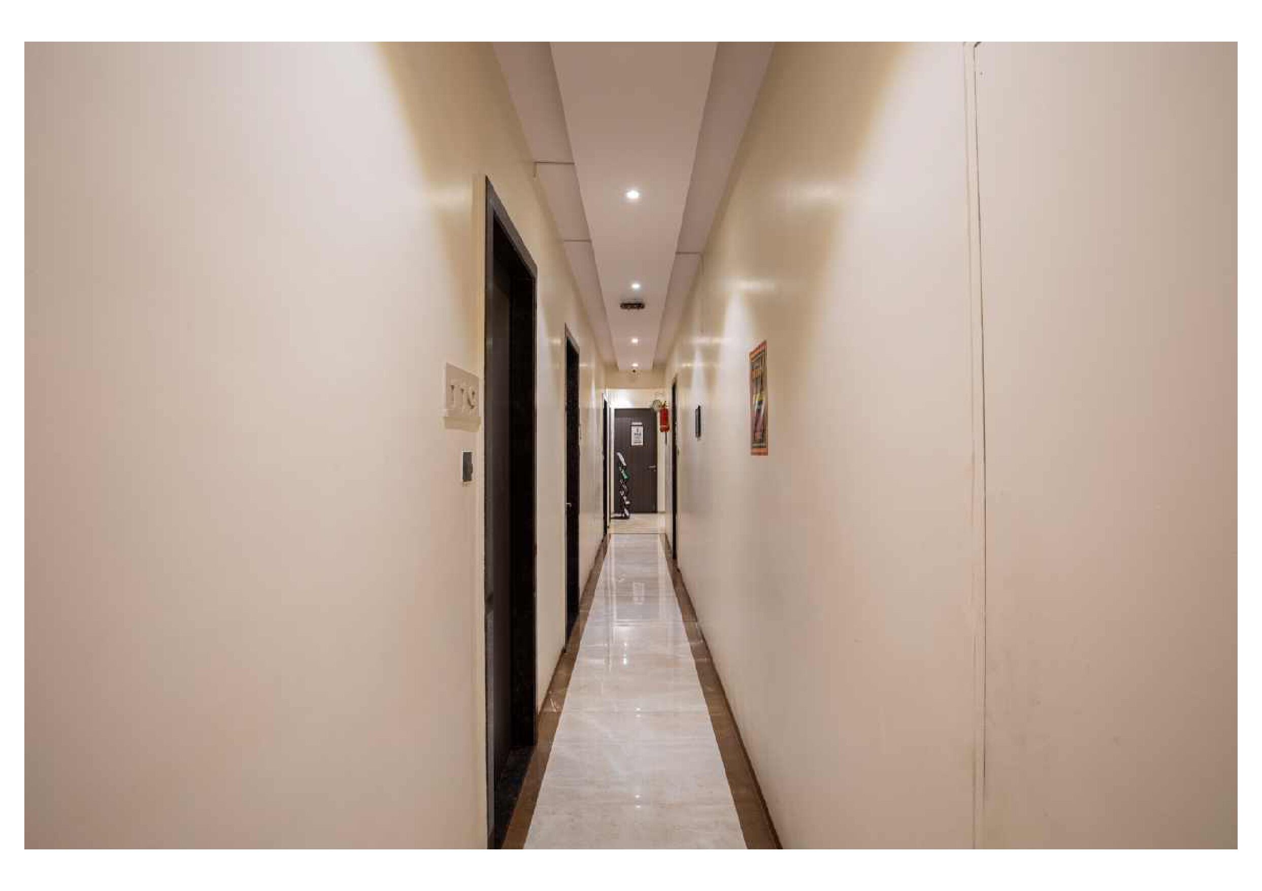 Un couloir d’hôtel avec un sol en marbre, des murs de couleur claire et des portes de part et d’autre.