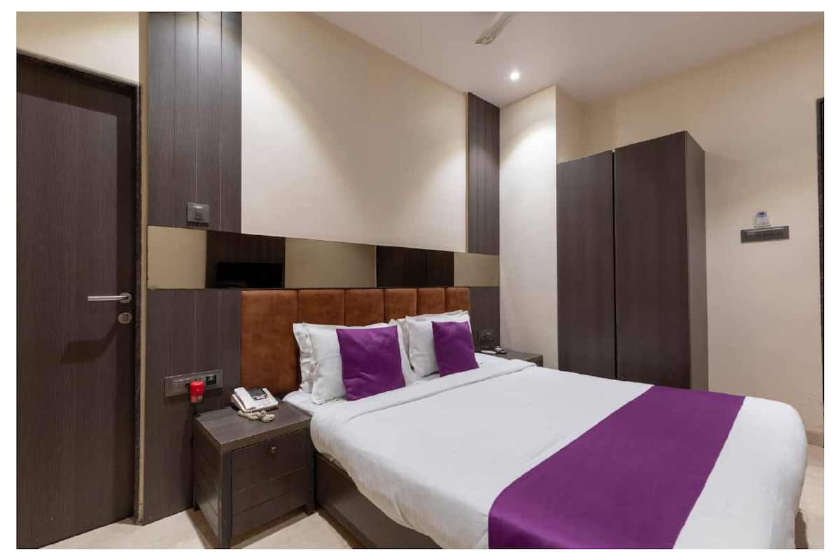 Ein Hotelzimmer mit einem großen Bett, einem Nachttisch, einem Kleiderschrank und einer Tür.