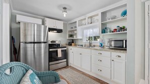 A modern kitchen with white cabinets, stainless steel appliances, and a built-in microwave.