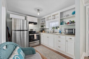 Una cocina moderna con gabinetes blancos, electrodomésticos de acero inoxidable y un microondas integrado.