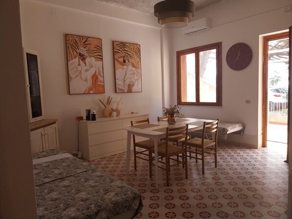 A compact living space with a dining area, a sofa, and artwork on the walls.
