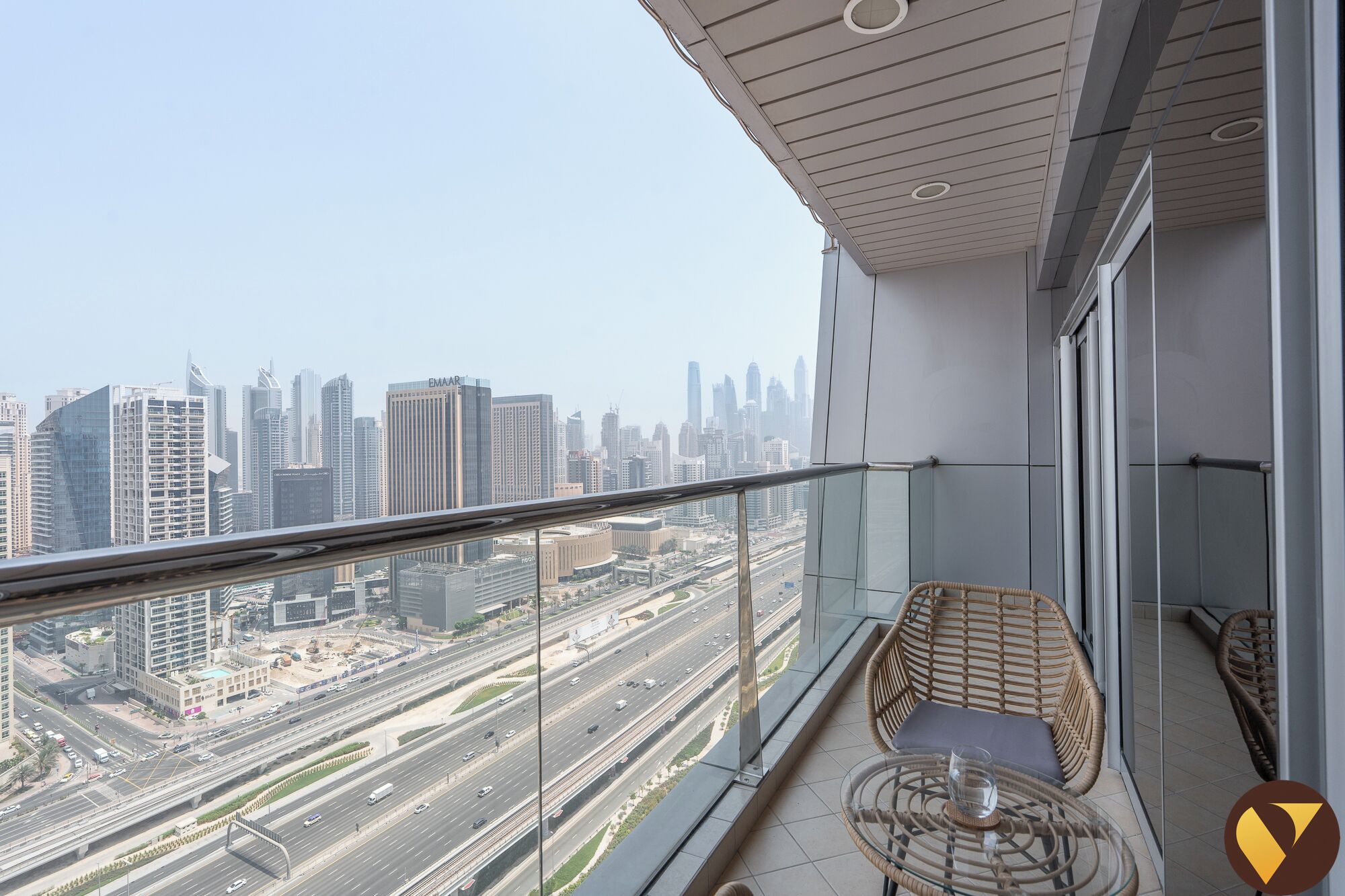 A balcony with a view of a cityscape, including a highway and tall buildings.