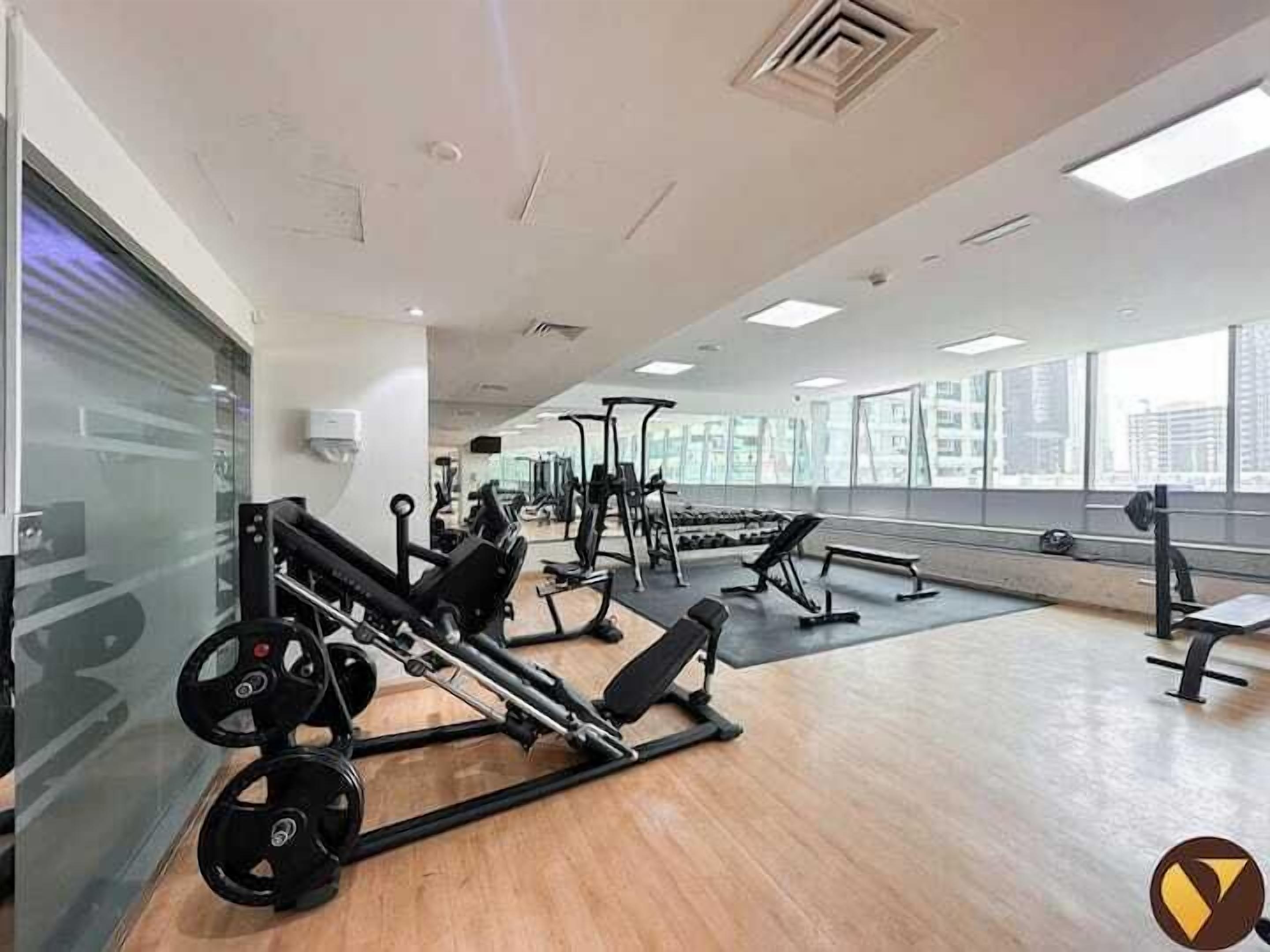 A gym with cardio machines, weight benches, and mirrors.