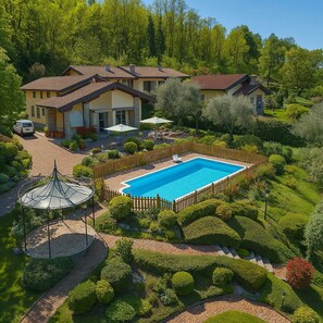 A large swimming pool surrounded by a wooden fence, with a gazebo and a well-maintained garden.