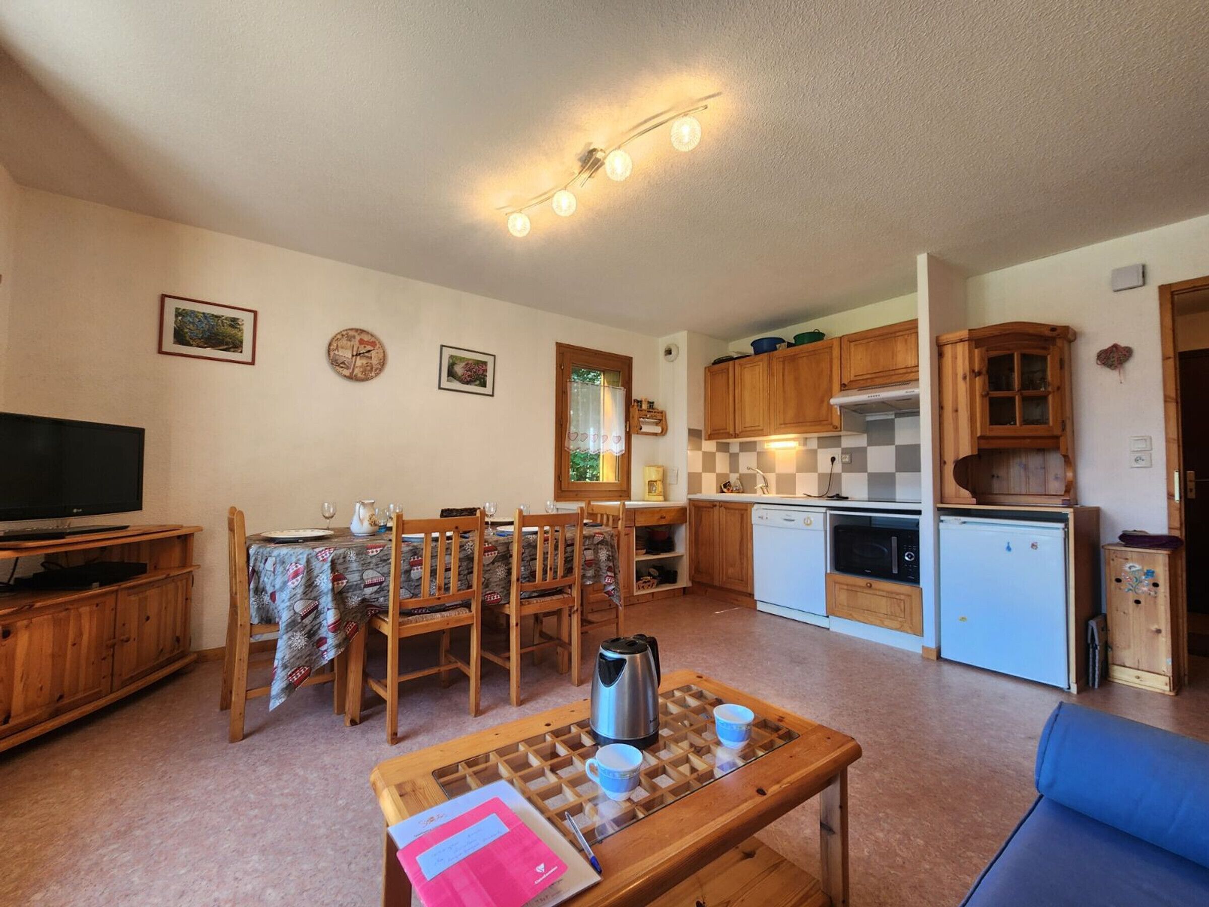 Een knus woongedeelte met een eethoek, kitchenette en een televisie.