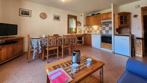 A compact living space with a dining area, kitchenette, and a TV. - Quiet T3 in Samoëns, near center, WIFI, private parking (Samoëns)
