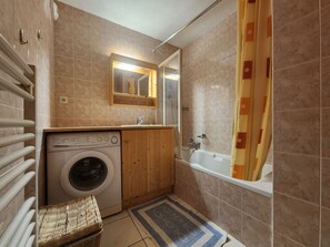 A compact bathroom with a washing machine, a bathtub, and a shower. - Quiet T3 in Samoëns, near center, WIFI, private parking (Samoëns)