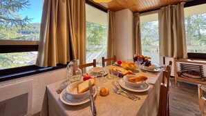 Mesa posta com pão, fruta e copos, com vista panorâmica.