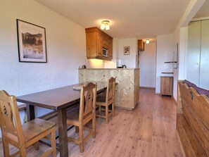 A compact kitchen with wooden cabinets, a dining table with chairs, and a small island. - Comfortable 3-room near slopes and shops, 6 pers, Méribel (Méribel)