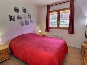 A bedroom with a bed, a nightstand, a lamp, a window with curtains, and wall art. - Comfortable 3-room near slopes and shops, 6 pers, Méribel (Méribel)