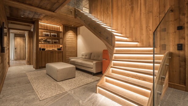 A wooden interior with a staircase, a sofa, and a small table.
