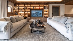 A cozy living room with two sofas, a coffee table, and a wooden bookshelf with books and decorative items.