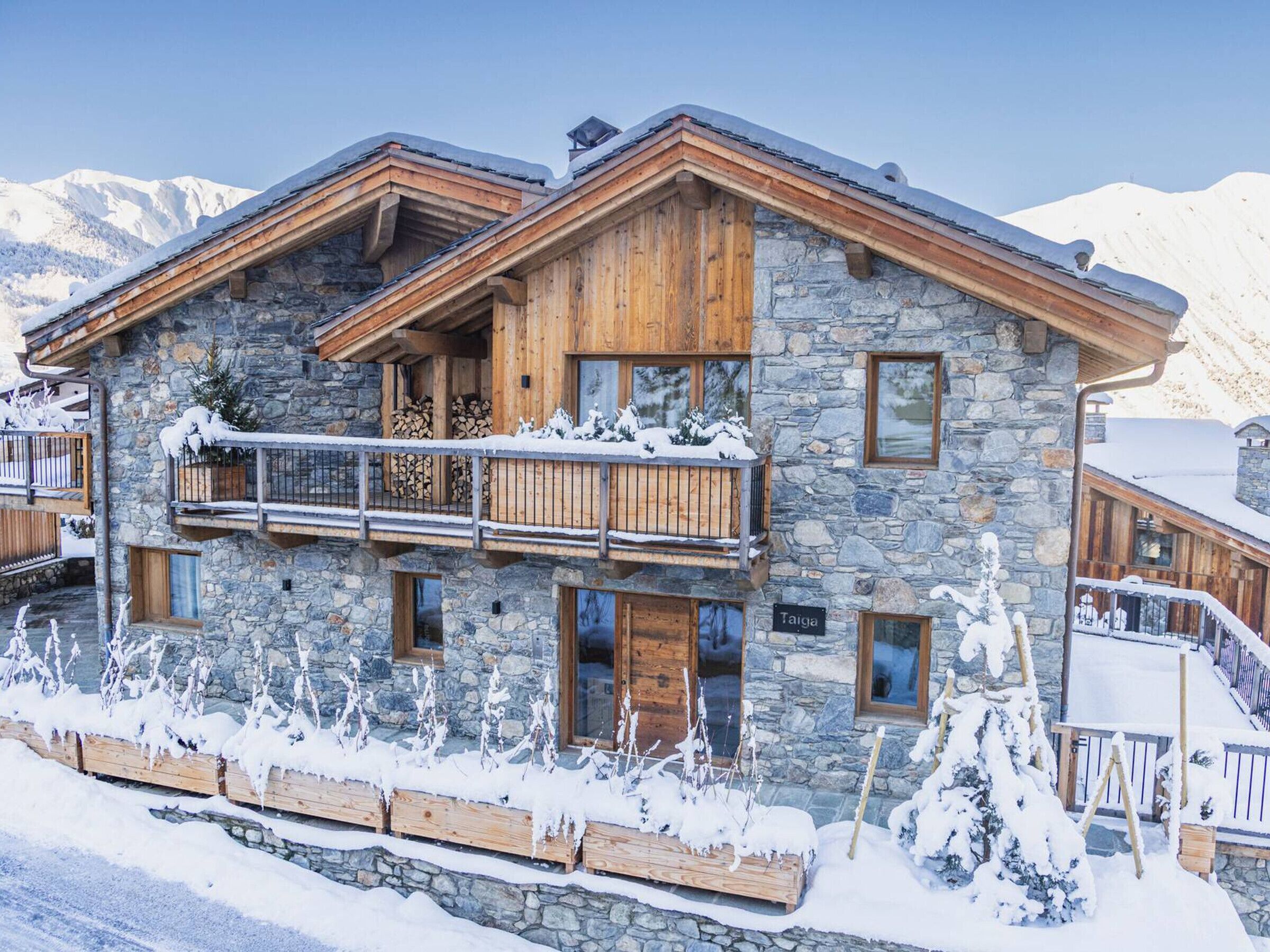Un chalet en pierre et en bois doté d’un balcon, de balustrades en bois et d’une enseigne indiquant le mot « Taïga ».
