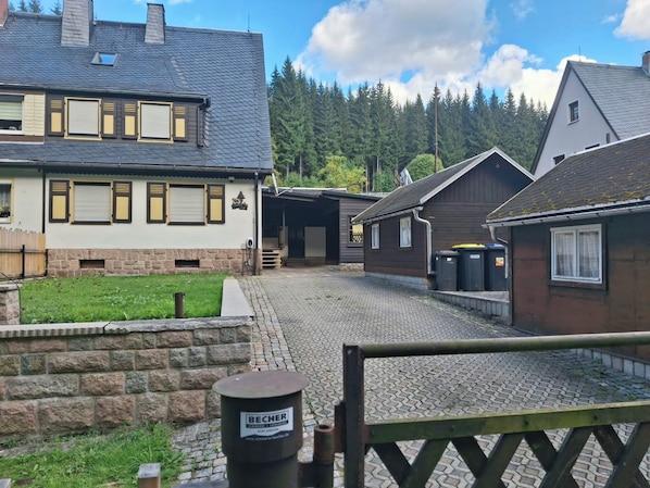 A residential street with houses, a cobblestone path, and a wooden gate. - Vacation home Oberwildenthal M.ORE MOUNTAINS CHALET 110sqm (Eibenstock)