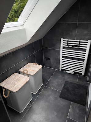 A modern bathroom with a skylight, two wooden stools, a towel rack, and a radiator. - Vacation home Oberwildenthal M.ORE MOUNTAINS CHALET 110sqm (Eibenstock)