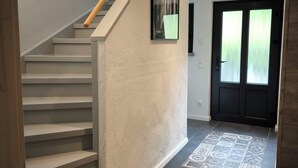 A modern staircase with a wooden handrail leading to a dark door with frosted glass panels. - Vacation home Oberwildenthal M.ORE MOUNTAINS CHALET 110sqm (Eibenstock)