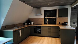 A modern kitchen with a built-in oven, a coffee maker, and a sink. - Vacation home Oberwildenthal M.ORE MOUNTAINS CHALET 110sqm (Eibenstock)