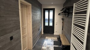 A hallway with a wooden door, a black-framed door, and a bench. - Vacation home Oberwildenthal M.ORE MOUNTAINS CHALET 110sqm (Eibenstock)