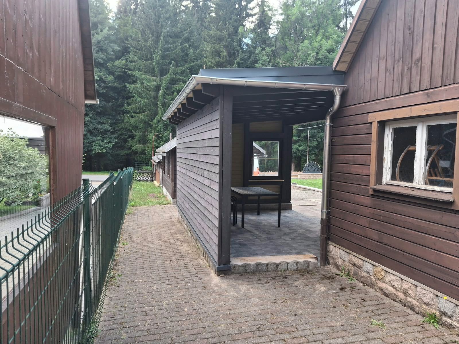Un edificio de madera con un área de estar al aire libre cubierta y un sendero pavimentado.