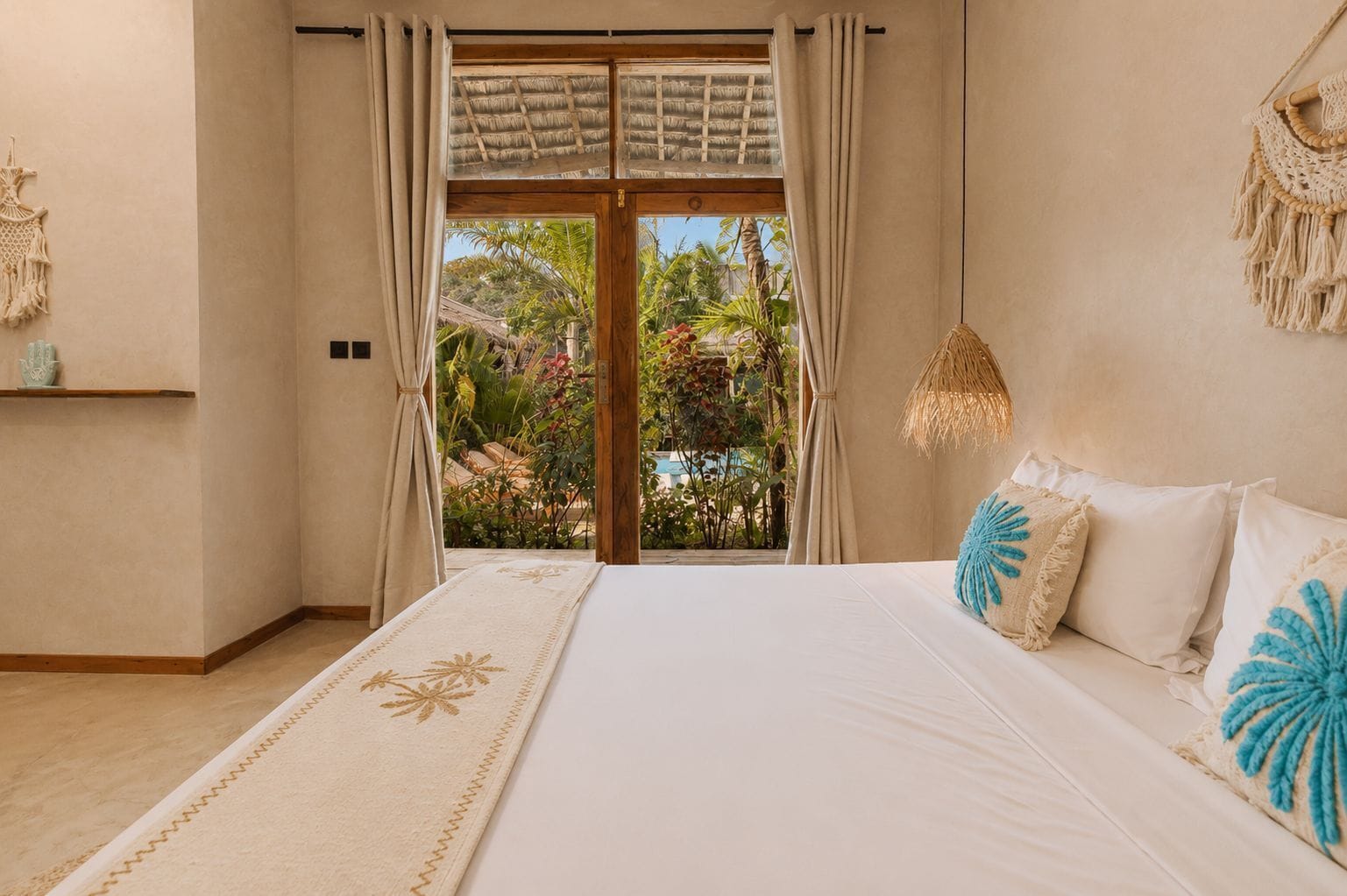 Une chambre avec un grand lit, une vue sur la verdure et une décoration murale en macramé.
