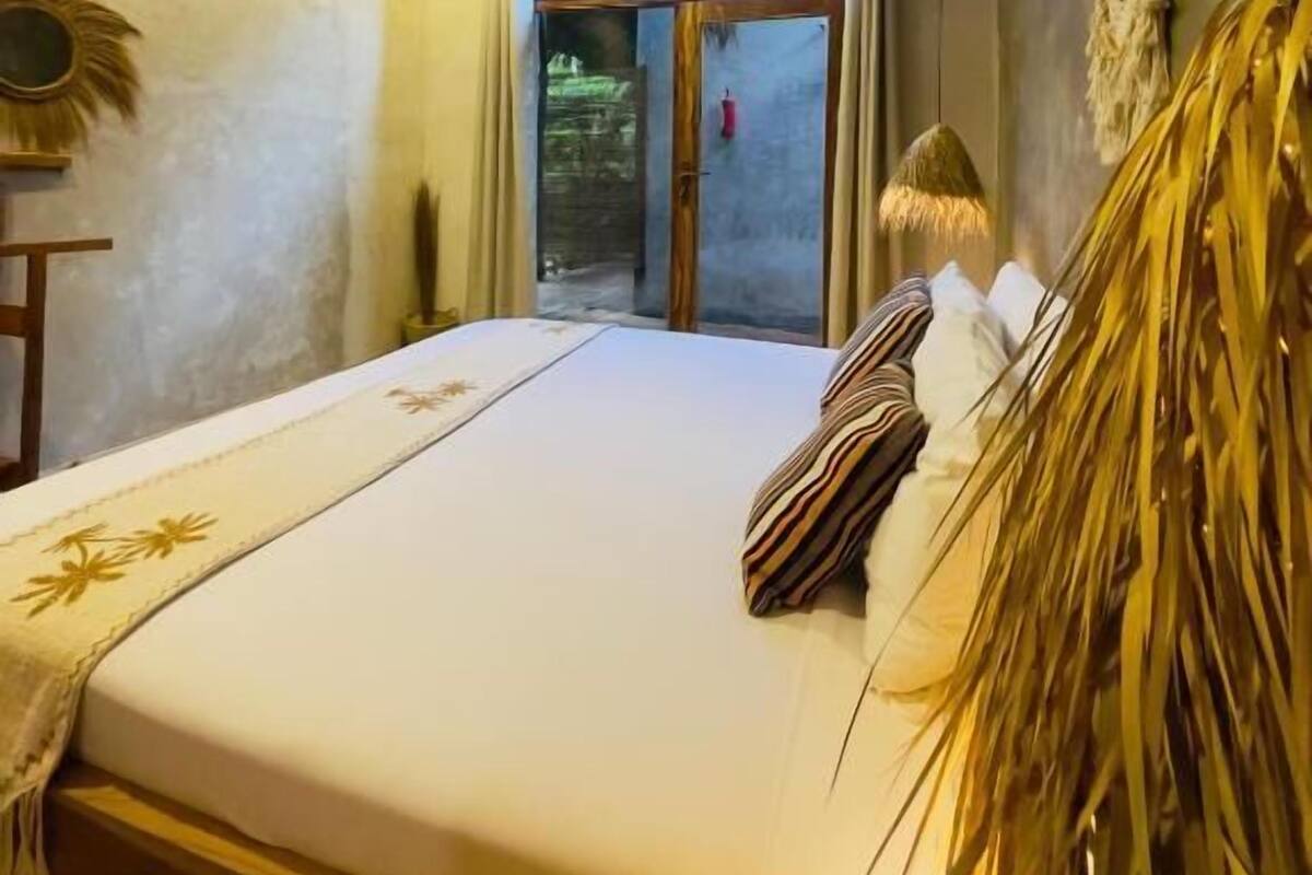 Ein Schlafzimmer mit Bett, Deckenventilator, Fenster mit Vorhängen und Wanddekoration.