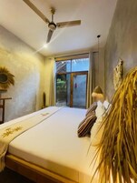 A bedroom with a bed, a ceiling fan, a window with curtains, and a wall-mounted decoration.