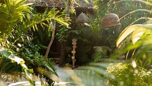 Un jardin tropical doté d’une structure à toit de chaume, d’un sentier et d’un panneau indicateur avec des numéros.