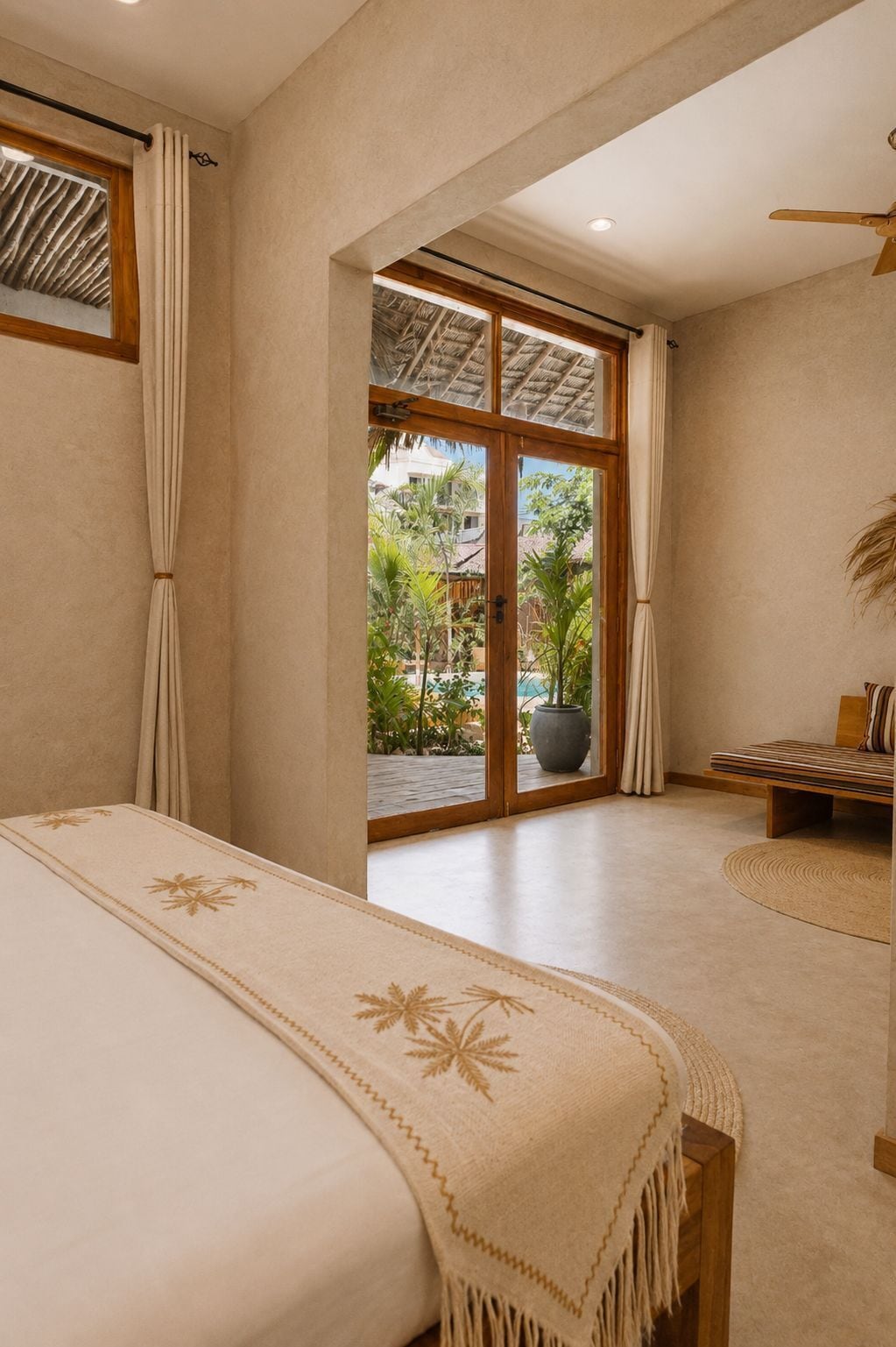 A bedroom with a bed, a window, a ceiling fan, and a view of greenery outside.