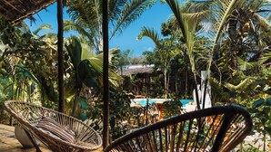 Un espace extérieur de style tropical, avec des fauteuils en osier, une piscine et une végétation luxuriante.