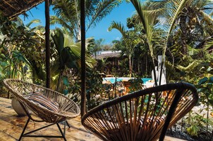 A tropical outdoor area with wicker chairs, a pool, and lush greenery.