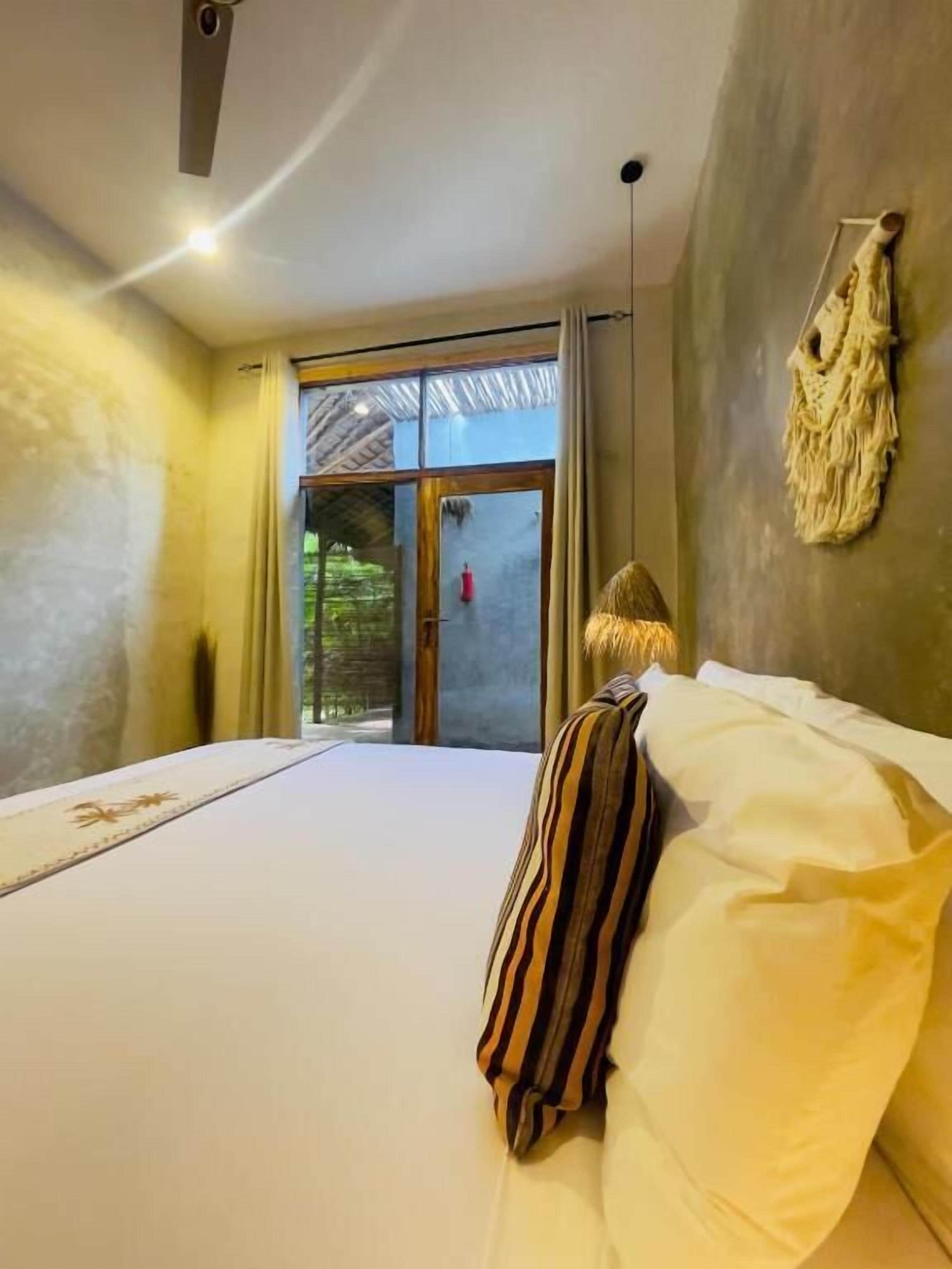 A bedroom with a bed, a view of the outdoors, and a door leading outside.