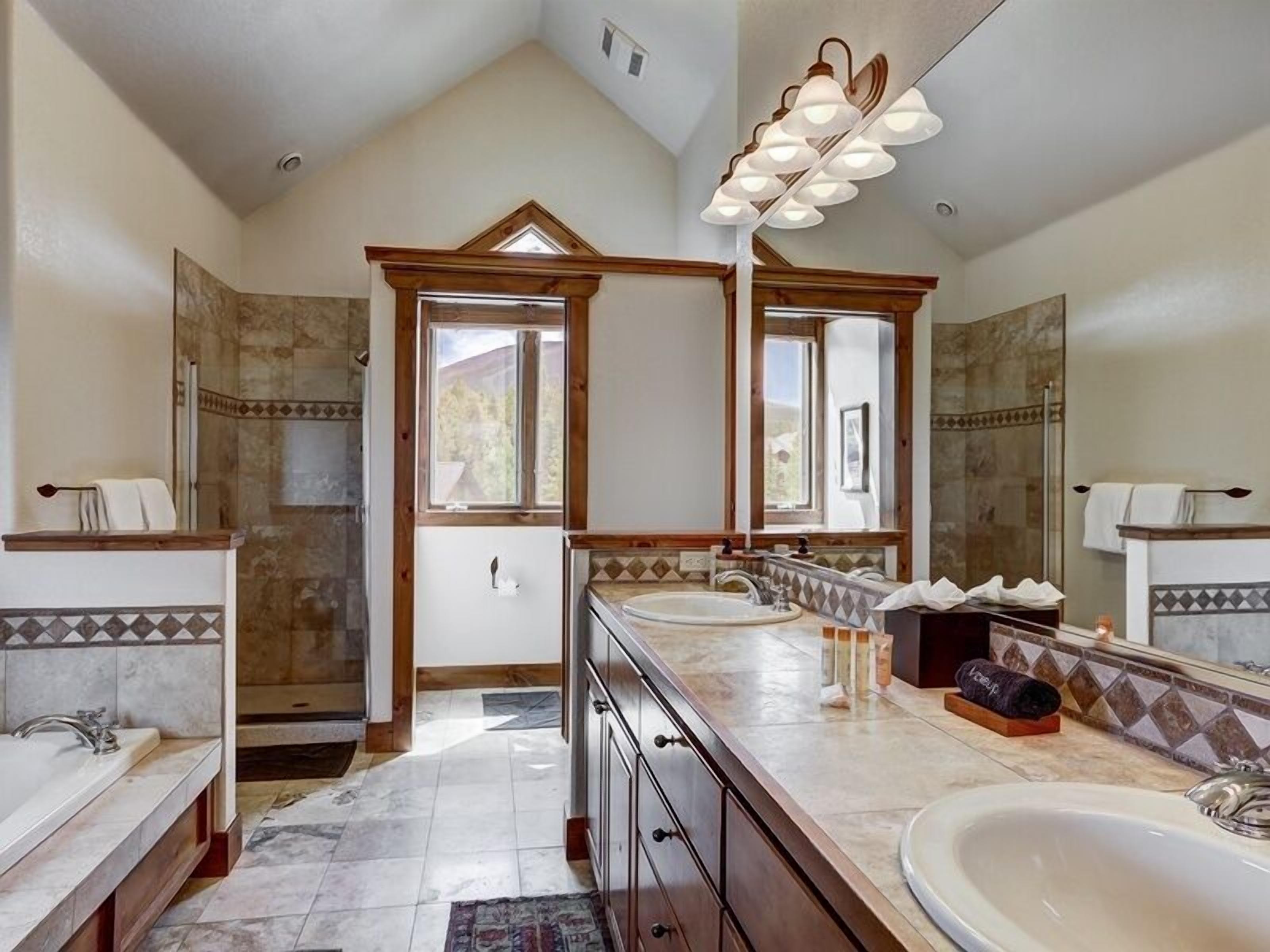 A spacious bathroom with a large vanity, double sinks, a bathtub, and a walk-in shower.