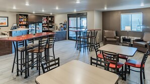 A modern dining area with high tables and chairs, a bar area with a counter, and a seating area with sofas and a coffee table.