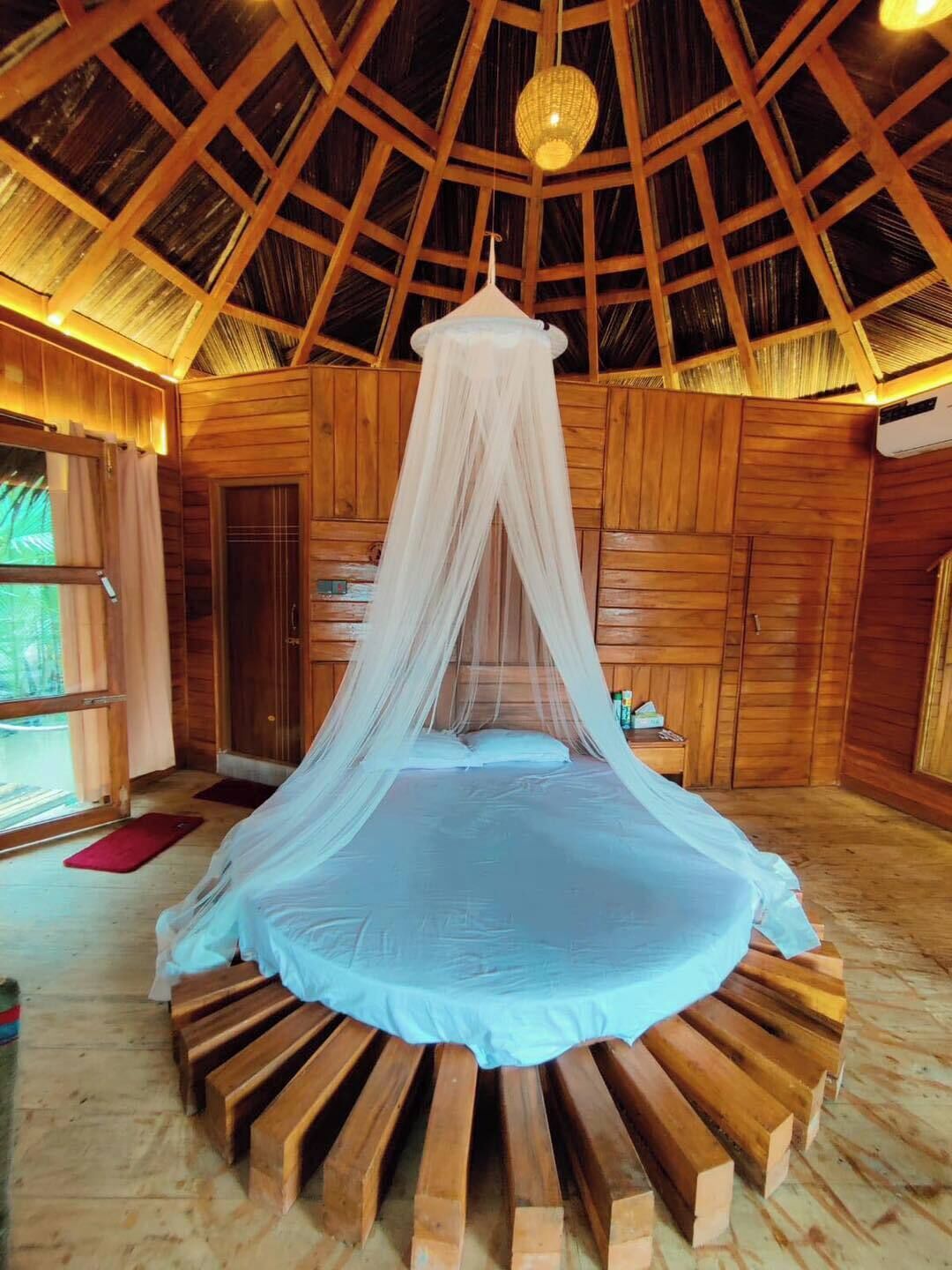 A room with a bed under a canopy, wooden walls, and a sloped ceiling.