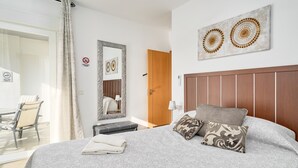 A hotel room with a bed, a wooden headboard, a mirror, and a view of the outside. - Apartment 'Sea and Mountain Views' with Sea View, Shared Pool, and AC (Torrox)