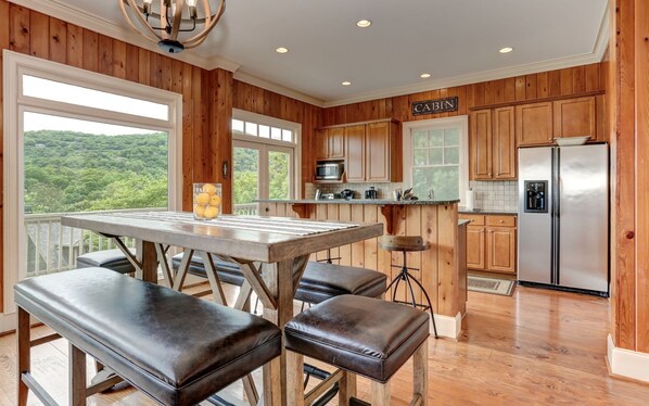 A kitchen with wooden cabinets, a stainless steel refrigerator, and a large window overlooking a forested area. - Big Canoe - Steps to Amenities & Pet friendly - must disclose (Jasper)