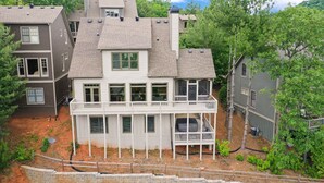 Een meerlaags huis met een balkon, een overdekte veranda en een omheinde tuin.