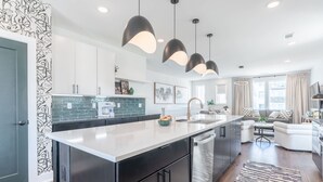 A modern kitchen with a central island, black cabinetry, and pendant lighting. - Luxe 4BR Retreat With Rooftop Fire Pit Garage (Nashville)