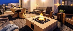 A rooftop patio with a fire pit, outdoor seating, and a view of buildings in the background. - Luxe 4BR Retreat With Rooftop Fire Pit Garage (Nashville)