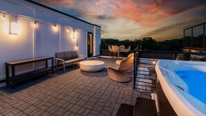 Un patio en la azotea con jacuzzi, zona de estar e iluminación ambiental.