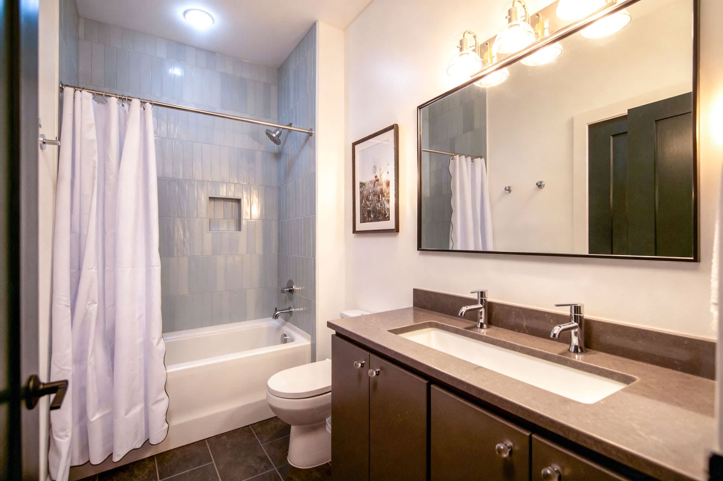 Une salle de bain moderne équipée d’une baignoire, de toilettes et d’un meuble-lavabo avec un miroir.
