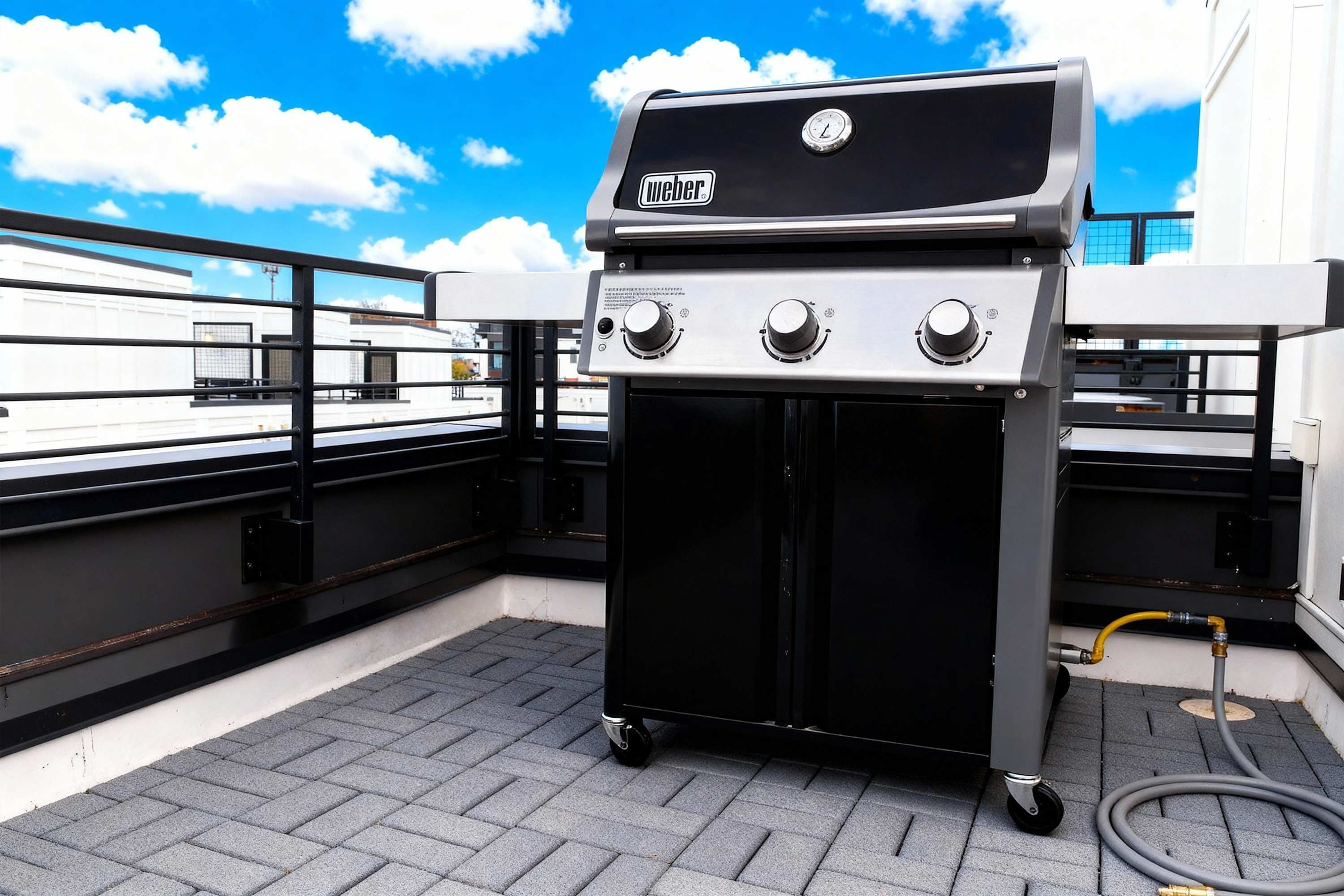 Una parrilla Weber portátil con tres quemadores en una terraza en la azotea.