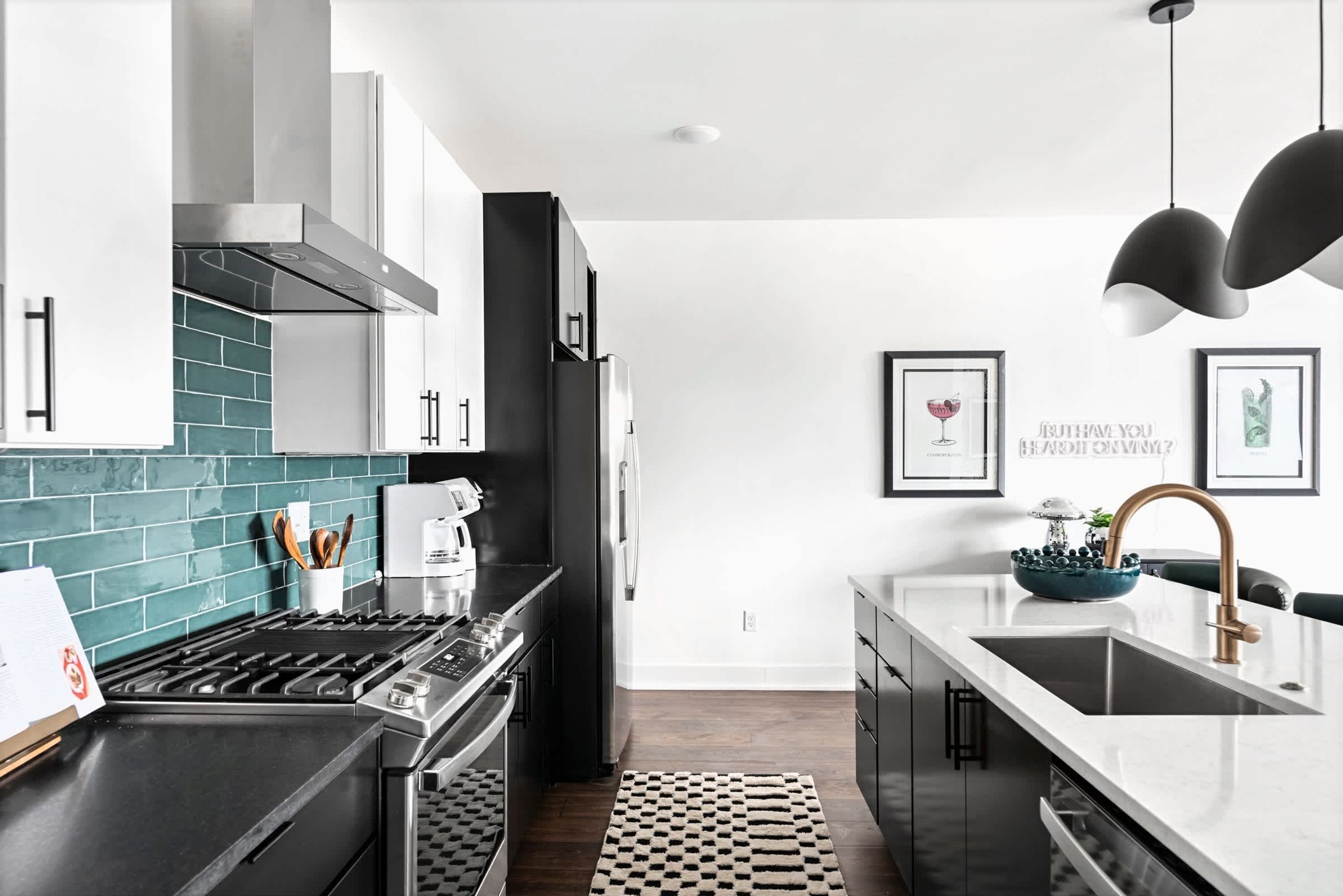 A modern kitchen with a black stove, stainless steel appliances, and a teal backsplash.