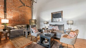 A cozy living room with a brick wall, a ceiling fan, a sofa, a coffee table, and a fireplace. - Peaceful and Private Retreat (Lafayette)