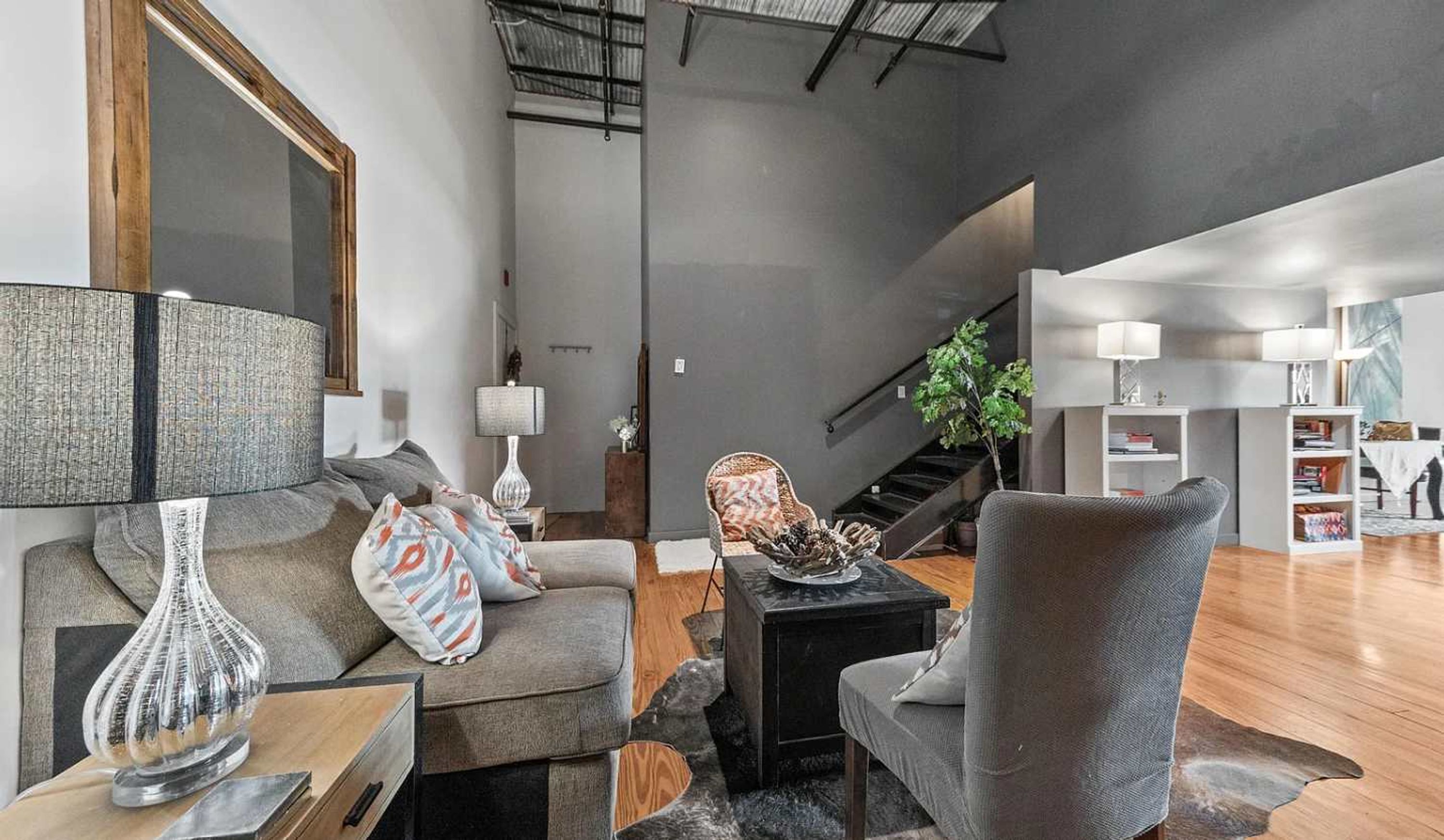 Ein modernes Wohnzimmer mit einer Couch, Sesseln, einem Couchtisch und einer Treppe zu einer weiteren Ebene.