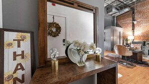 A modern living room with a wooden coffee table, a white vase with flowers, and a decorative wreath on the door. - Peaceful and Private Retreat (Lafayette)